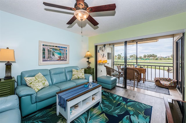 living room featuring ceiling fan, hardwood / wood-style floors, and a textured ceiling