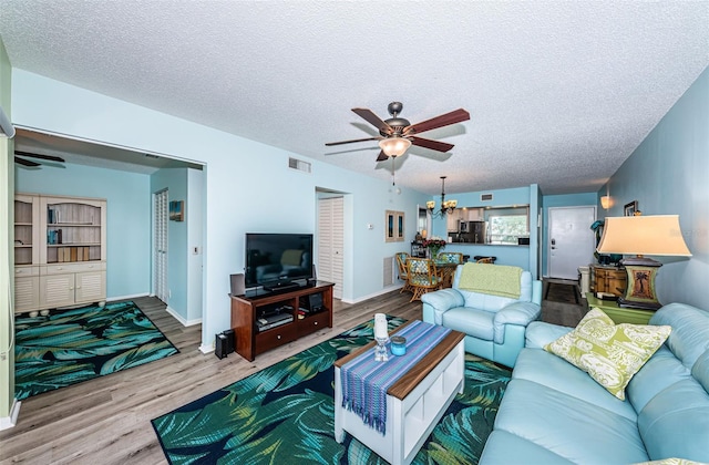 living room with ceiling fan with notable chandelier, a textured ceiling, and hardwood / wood-style flooring