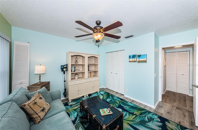 living room with ceiling fan, hardwood / wood-style floors, and a textured ceiling