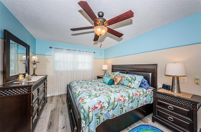 bedroom featuring ceiling fan, light hardwood / wood-style floors, and a textured ceiling