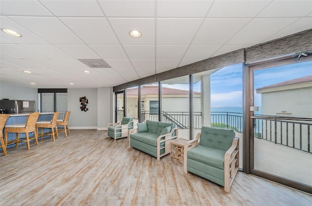 living room with a water view, light hardwood / wood-style flooring, and floor to ceiling windows