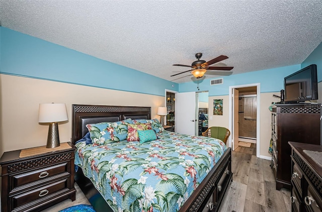 bedroom with ensuite bath, ceiling fan, light hardwood / wood-style flooring, and a textured ceiling