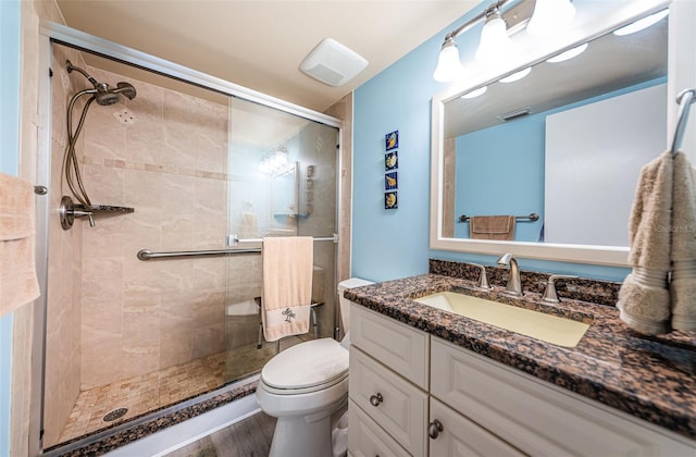 bathroom with an enclosed shower, vanity, toilet, and wood-type flooring