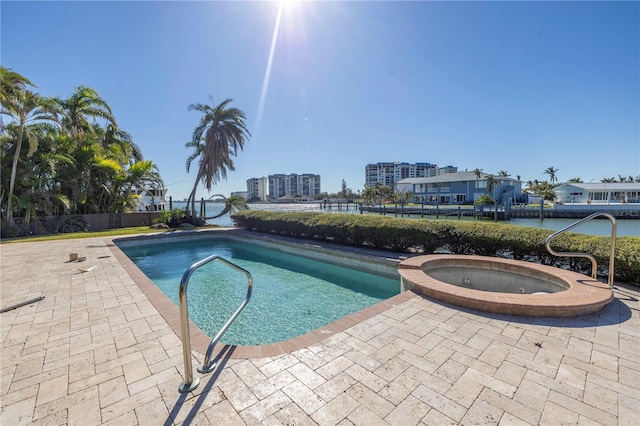 view of swimming pool with an in ground hot tub, a water view, and a patio area