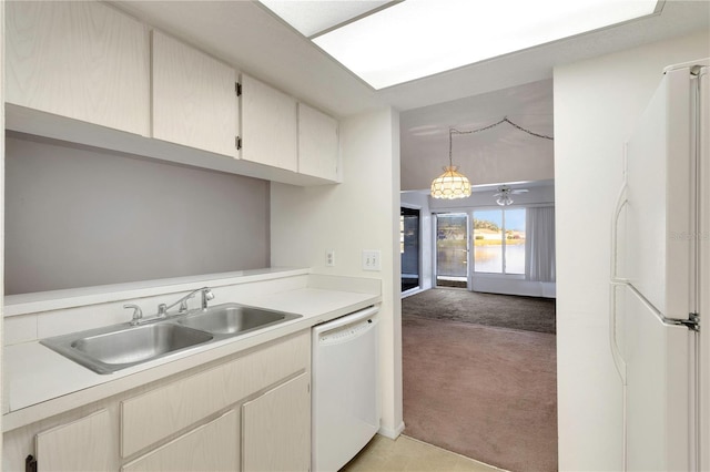 kitchen with sink, white appliances, light carpet, and hanging light fixtures