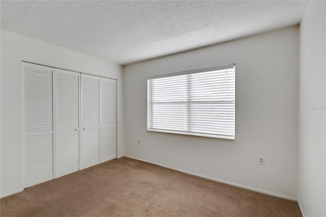 unfurnished bedroom featuring carpet, a closet, and a textured ceiling