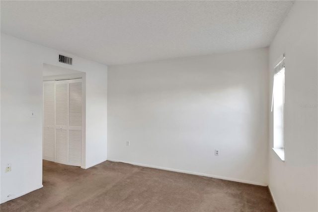 carpeted empty room with a textured ceiling