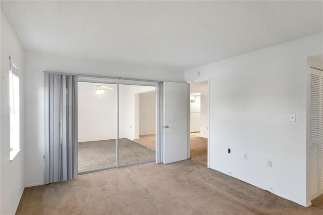 unfurnished bedroom featuring light carpet, a closet, and a textured ceiling