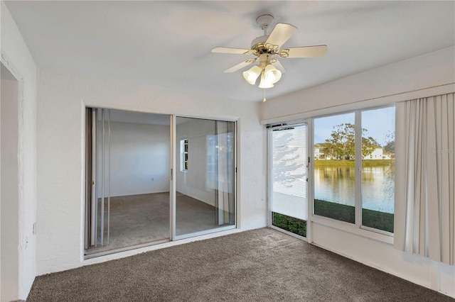 carpeted spare room with ceiling fan and a water view