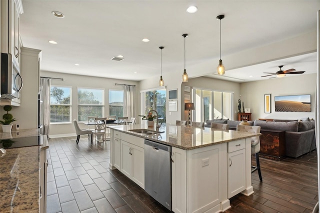 kitchen featuring a kitchen island with sink, sink, decorative light fixtures, dark hardwood / wood-style flooring, and stainless steel appliances