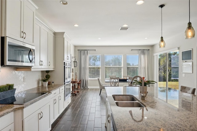 kitchen featuring light stone countertops, appliances with stainless steel finishes, a wealth of natural light, and sink