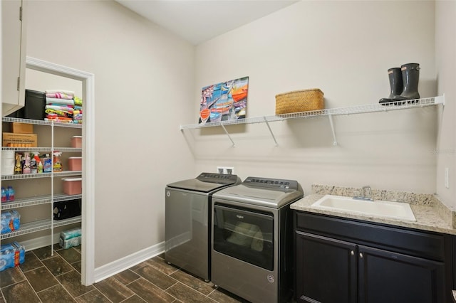 laundry area featuring washing machine and clothes dryer, dark hardwood / wood-style floors, cabinets, and sink