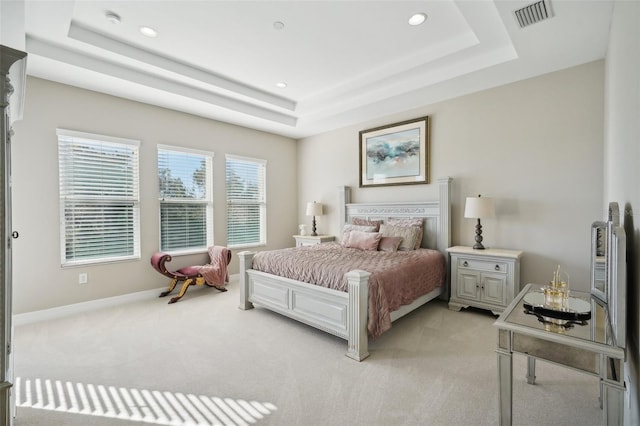 bedroom with light carpet and a raised ceiling