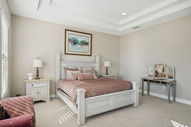 bedroom featuring a raised ceiling and light carpet