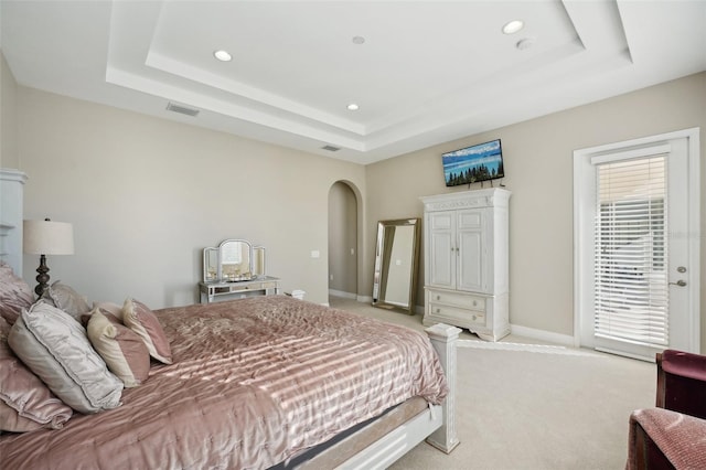 carpeted bedroom with a raised ceiling