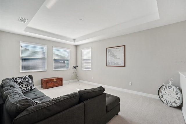 living room with carpet floors and a tray ceiling