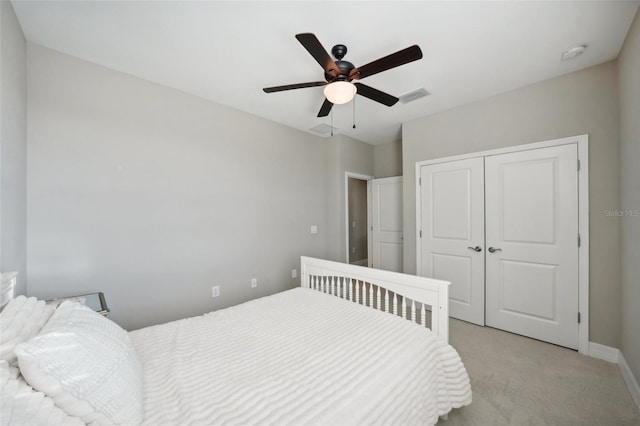 bedroom with ceiling fan, light colored carpet, and a closet