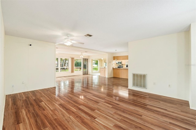 unfurnished living room with ceiling fan, a textured ceiling, and hardwood / wood-style flooring