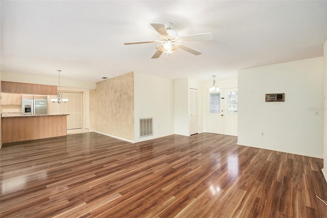 unfurnished living room featuring ceiling fan with notable chandelier and dark wood-type flooring