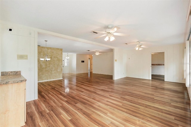 unfurnished living room featuring ceiling fan with notable chandelier and hardwood / wood-style flooring