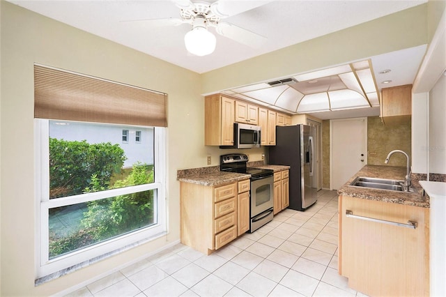 kitchen featuring appliances with stainless steel finishes, ceiling fan, sink, light brown cabinets, and light tile patterned floors