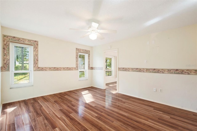 empty room with ceiling fan, dark hardwood / wood-style flooring, and plenty of natural light