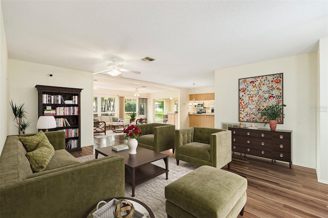 living room with ceiling fan, wood-type flooring, and a textured ceiling