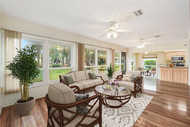 living room featuring wood-type flooring, a textured ceiling, and ceiling fan