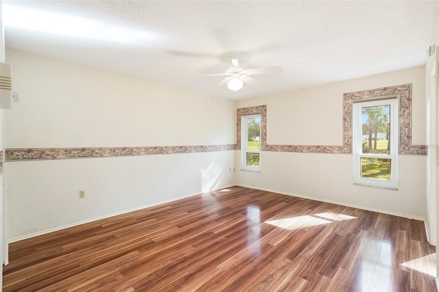 empty room with ceiling fan, dark wood-type flooring, and a textured ceiling