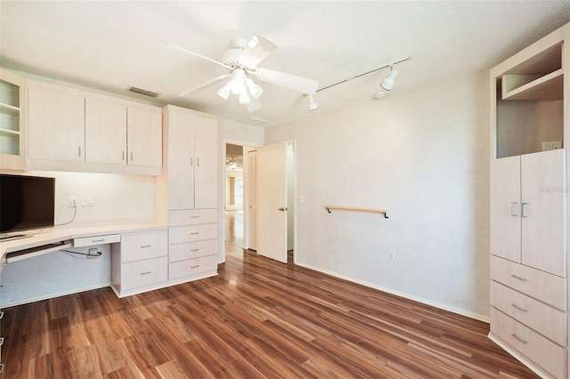 unfurnished office with ceiling fan, built in desk, and dark hardwood / wood-style floors