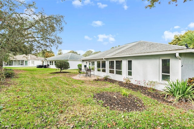 rear view of house featuring a lawn and a patio