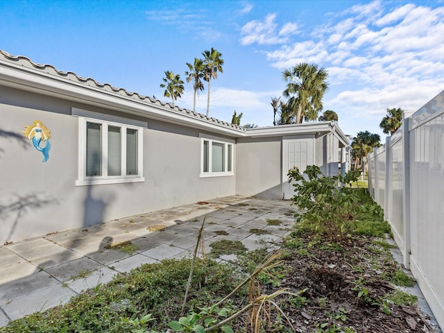 35 Juniper Way, Clearwater Beach, FL 33767 - view of side of home with stucco siding, a patio, and a tiled roof