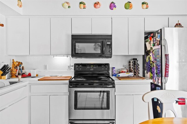 1202 Sawdust Ct, Valrico, FL 33596 - kitchen featuring black microwave, stainless steel range with electric stovetop, light countertops, white cabinets, and freestanding refrigerator