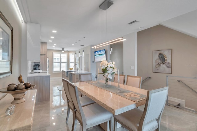 dining space featuring ceiling fan, sink, and vaulted ceiling