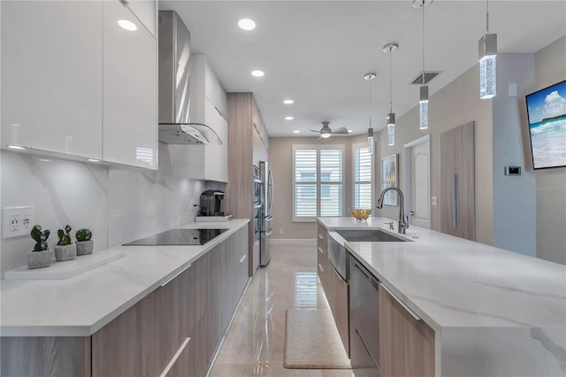 kitchen featuring hanging light fixtures, wall chimney exhaust hood, ceiling fan, light stone countertops, and white cabinetry