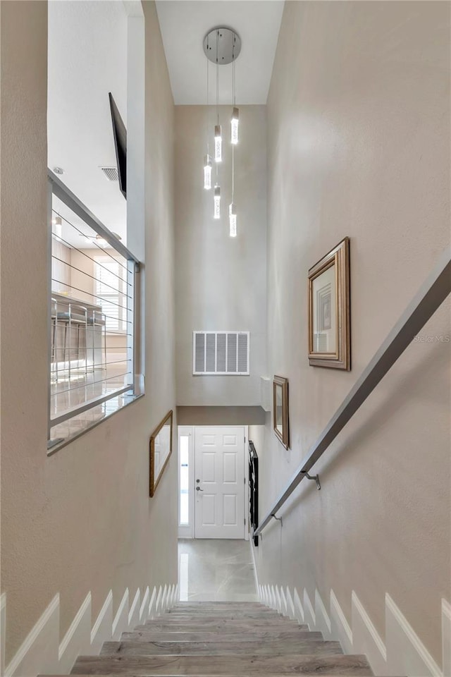 stairway with hardwood / wood-style floors and a high ceiling