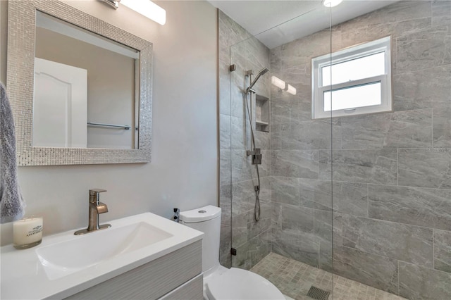 bathroom with a tile shower, vanity, and toilet