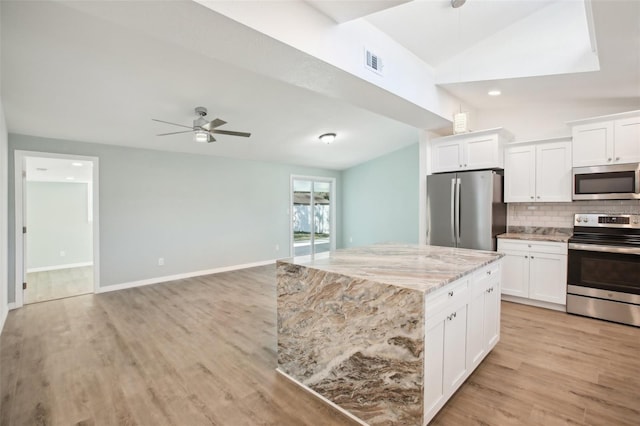 kitchen featuring white cabinets, stainless steel appliances, light stone countertops, and lofted ceiling