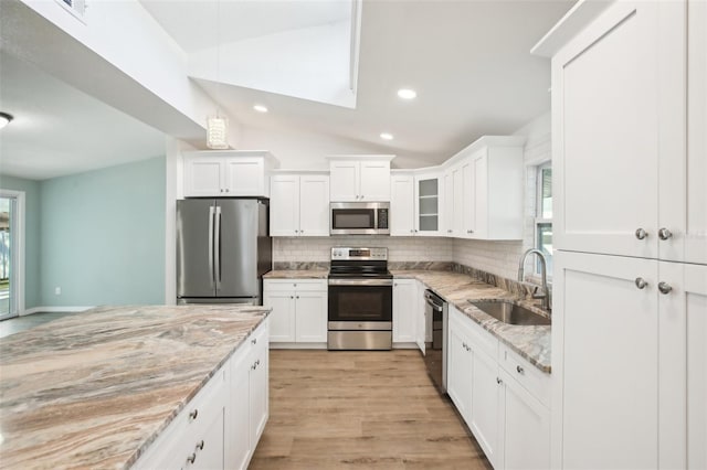 kitchen with light stone counters, sink, white cabinets, and appliances with stainless steel finishes