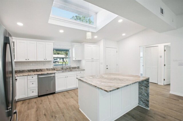 2537 Martha Ln, Land O Lakes, FL 34639 - kitchen featuring stainless steel appliances, a sink, vaulted ceiling, backsplash, and white cabinetry