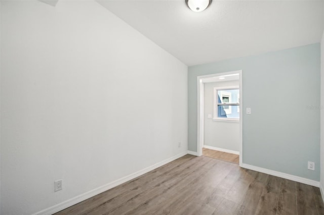 spare room with vaulted ceiling and hardwood / wood-style flooring