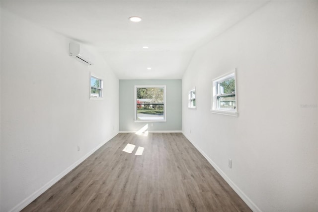 corridor featuring hardwood / wood-style floors, a wall unit AC, and vaulted ceiling