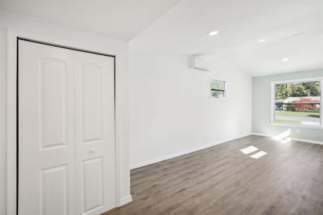 interior space with a wall mounted air conditioner, hardwood / wood-style floors, a closet, and lofted ceiling