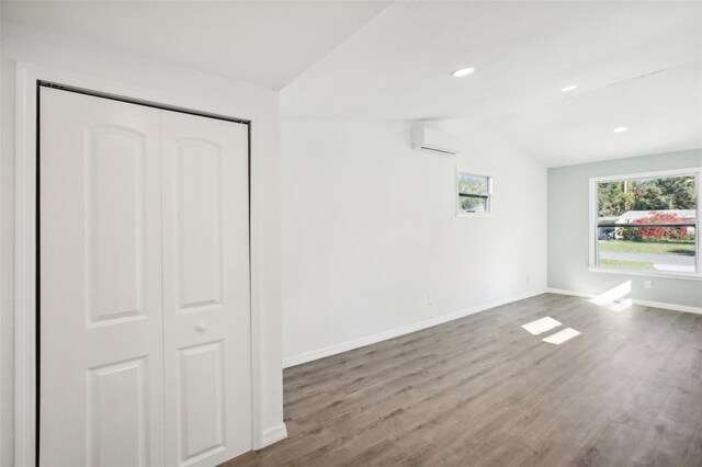 2537 Martha Ln, Land O Lakes, FL 34639 - unfurnished bedroom featuring a wall mounted air conditioner, lofted ceiling, baseboards, wood finished floors, and a closet