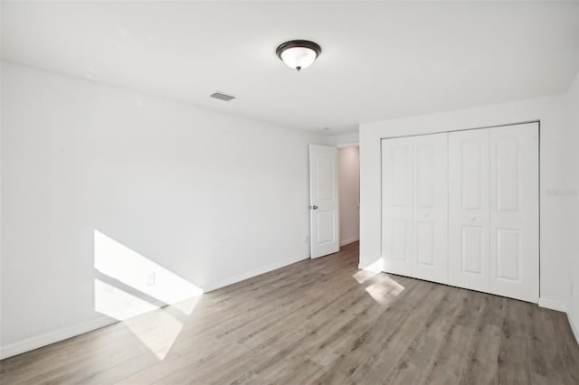 unfurnished bedroom with a closet and light wood-type flooring