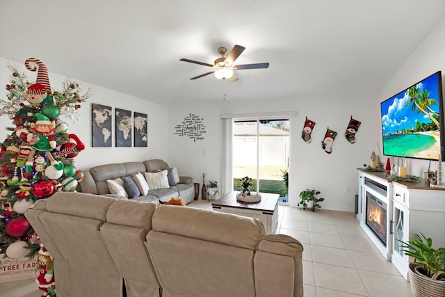 living room with a glass covered fireplace, light tile patterned flooring, and ceiling fan