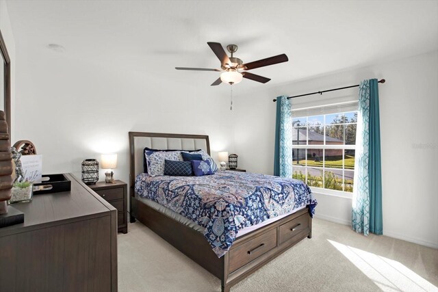 bedroom featuring light colored carpet, ceiling fan, and baseboards