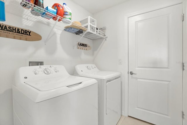 washroom featuring laundry area, light tile patterned floors, and washing machine and clothes dryer