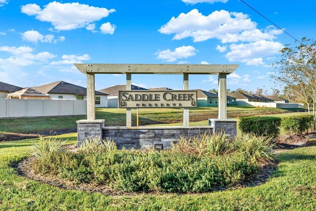 community sign featuring fence and a lawn