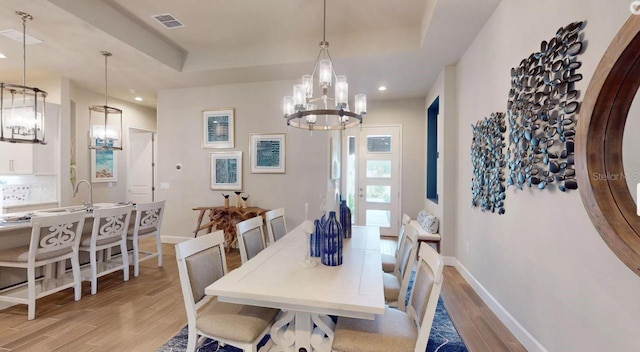 11 Regency Rd, Ormond Beach, FL 32174 - dining space with a chandelier, light wood finished floors, baseboards, recessed lighting, and a tray ceiling